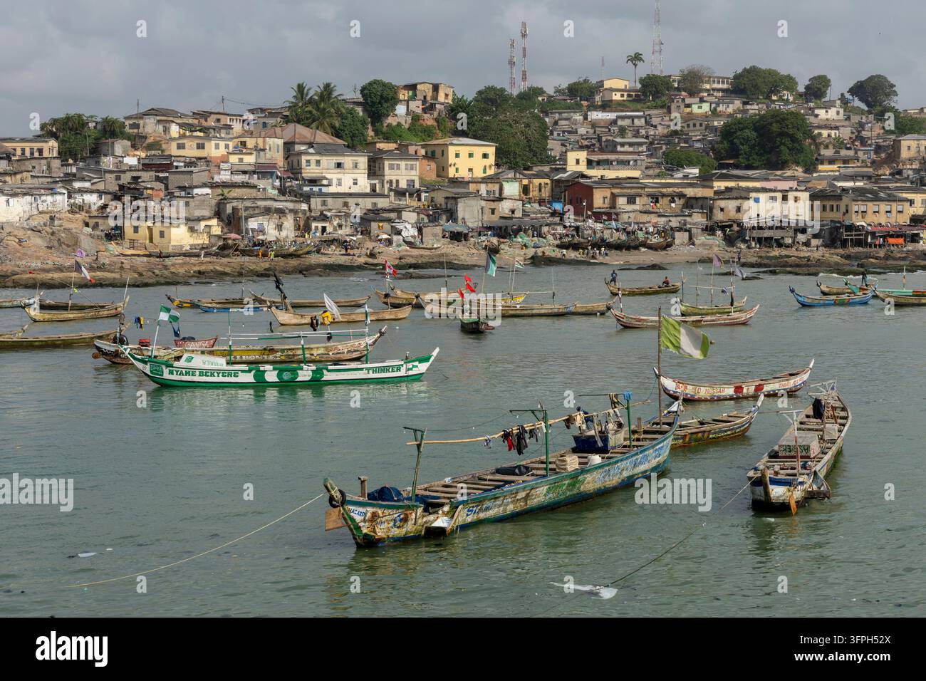Petits bateaux de pêche ancrés dans le port sous une ville de colline, Région centrale, Cape Coast, Ghana Banque D'Images