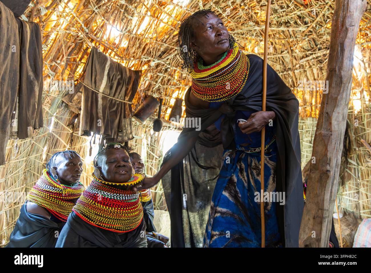 Femmes de la tribu Turkana portant des colliers de perles et des capes noires, rassemblées à l'intérieur d'une hutte en paille, comté de Marsabit, Loiyangalani, Kenya Banque D'Images