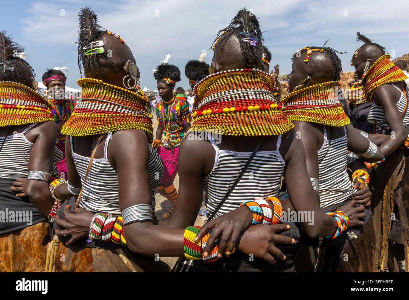 Femmes de la tribu Turkana en hauts rayés et colliers énormes de perles avec des plumes d'autruche, se tenant par le bras pour danser au Festival culturel du Lac Turkana, Marsabi Banque D'Images