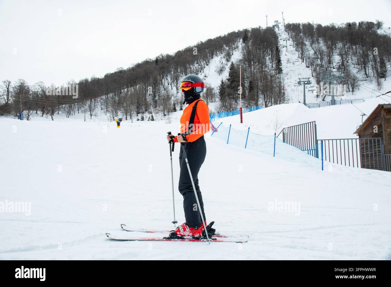 Ski. Skis prêts sur une pente enneigée dans une station de ski, portant une veste orange. Ski dans une station hivernale Banque D'Images
