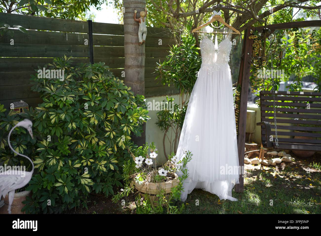 Belle robe de mariée blanche suspendue à un cintre dans un jardin luxuriant et vert Banque D'Images