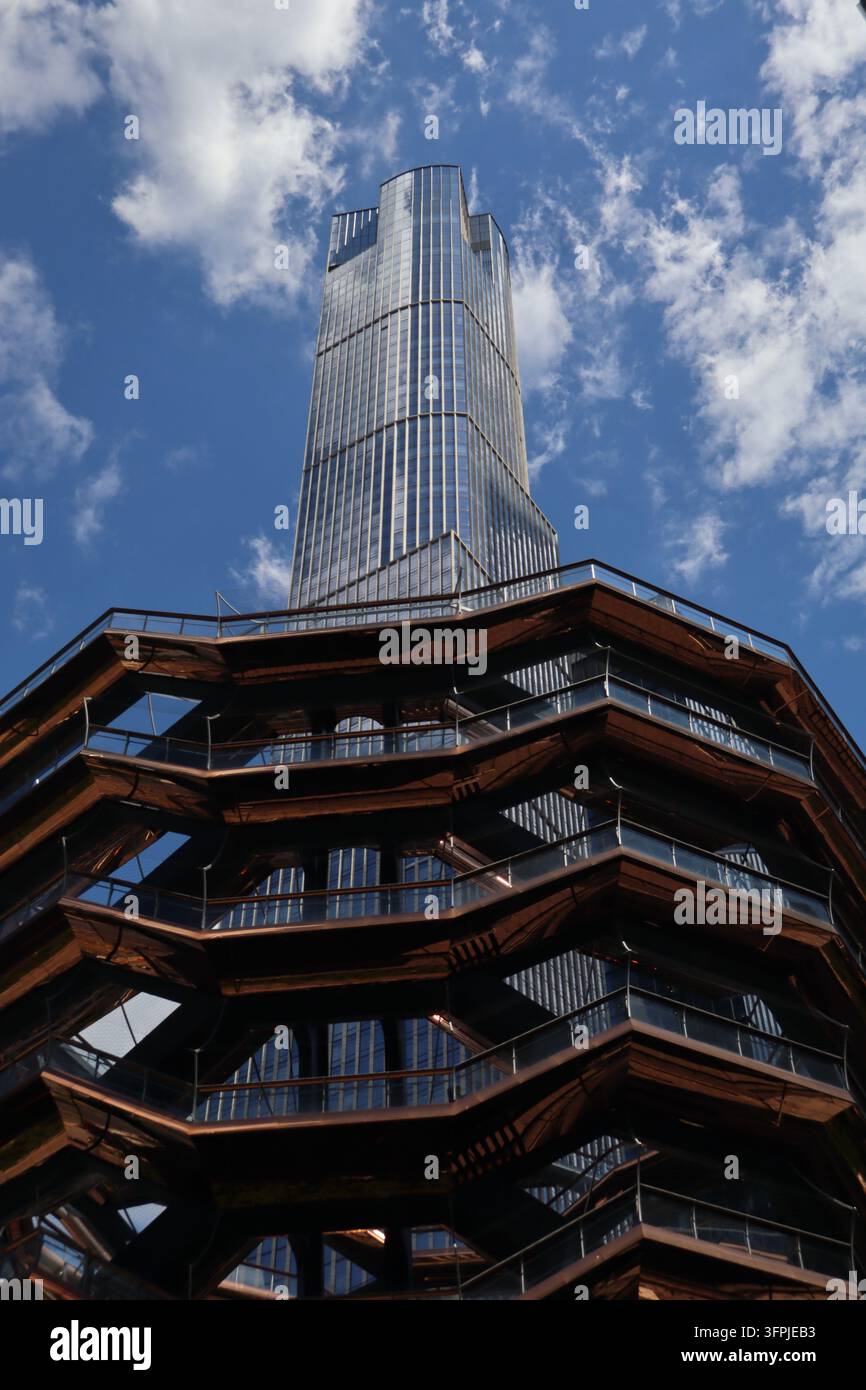 Le Vessel à Hudson Yards à Manhattan, New York City, avec ses escaliers couleur cuivre et un gratte-ciel moderne en verre qui s'élève en arrière-plan. Banque D'Images