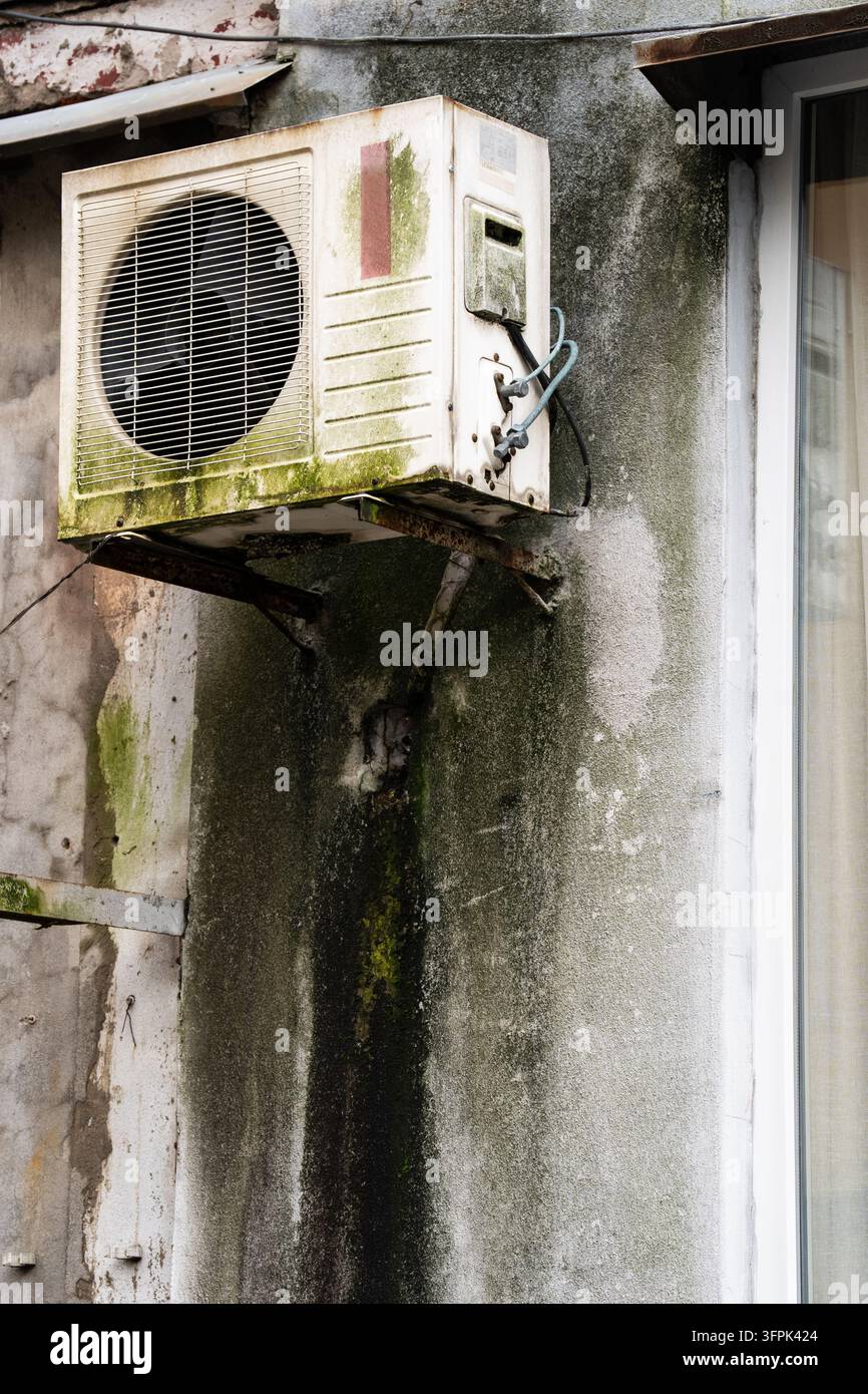 Ancienne unité de climatisation suspendue à un mur extérieur endommagé d'une maison résidentielle à Batumi, Géorgie. Banque D'Images