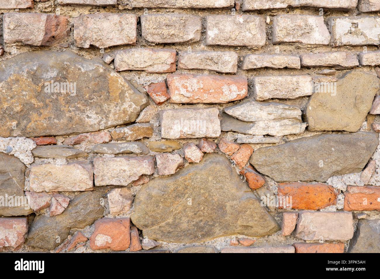 Une vue rapprochée d'un mur de pierre rustique rugueux fait de blocs de maçonnerie mélangés. Banque D'Images