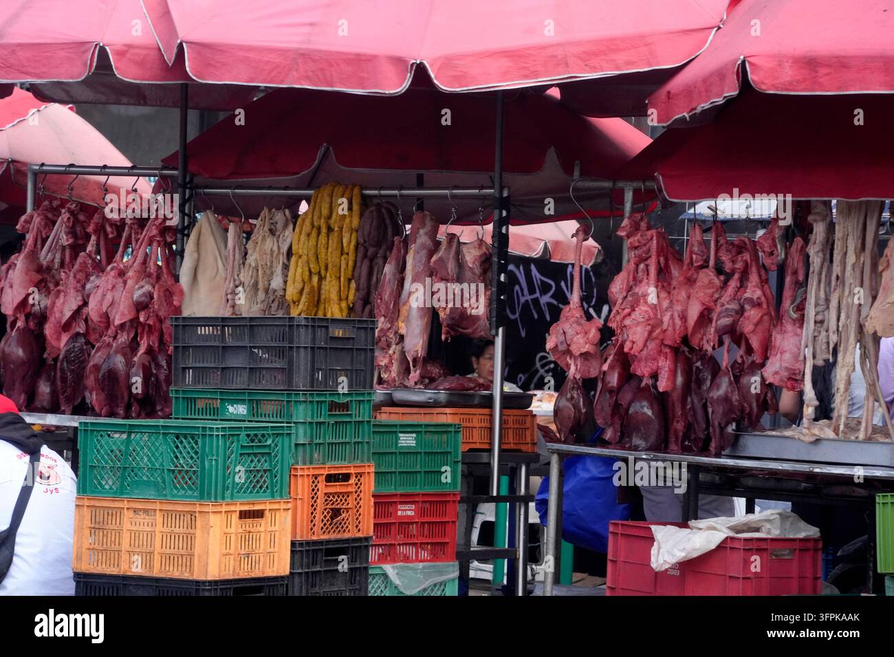 BOGOTA, COLOMBIE - 1ER NOVEMBRE 2025 : Viande fraîche crue et abats suspendus à des crochets sur un marché de rue animé à Bogota, Colombie. Banque D'Images