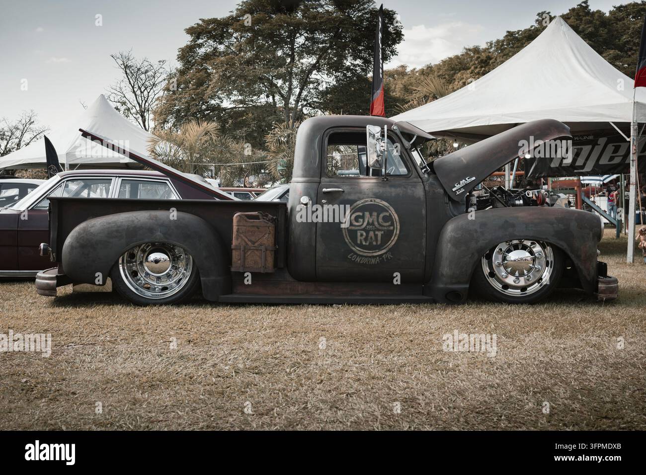 Vue latérale d'un pick-up vintage GMC rat rod avec suspension abaissée sur mesure, finition patina et roues chromées brillantes. Banque D'Images