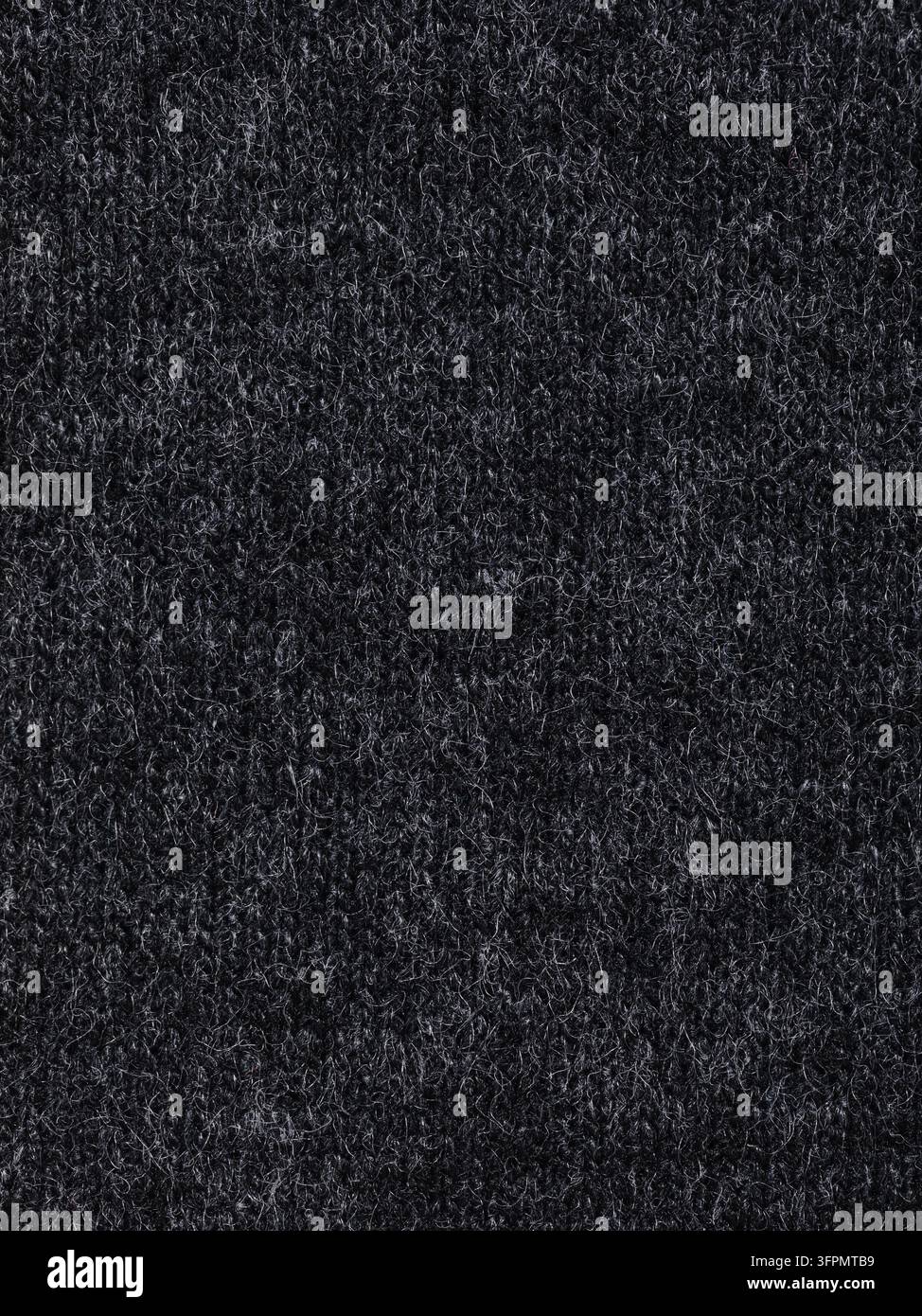 Texture macro d'un tissu tricoté en laine anthracite moelleux, fond textile sombre remplissant tout le cadre Banque D'Images