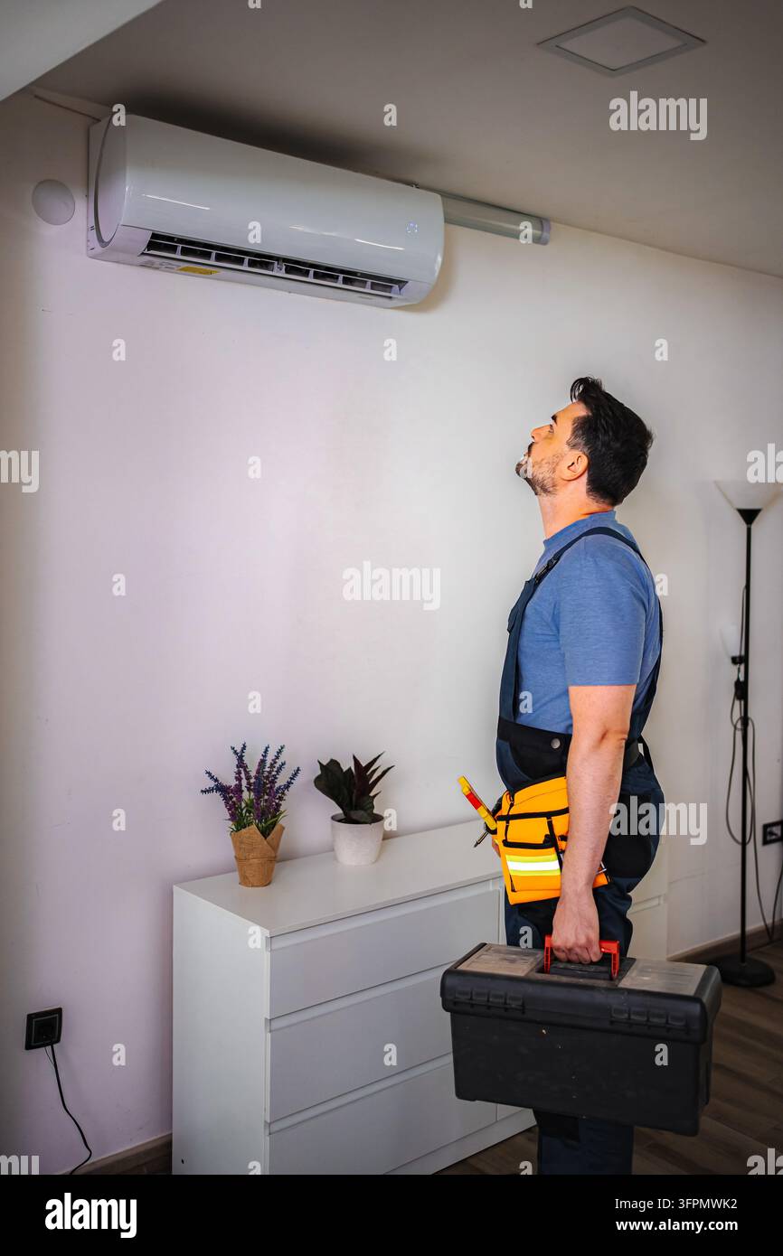 Technicien de climatisation vérifiant une unité de climatiseur à l'intérieur Banque D'Images