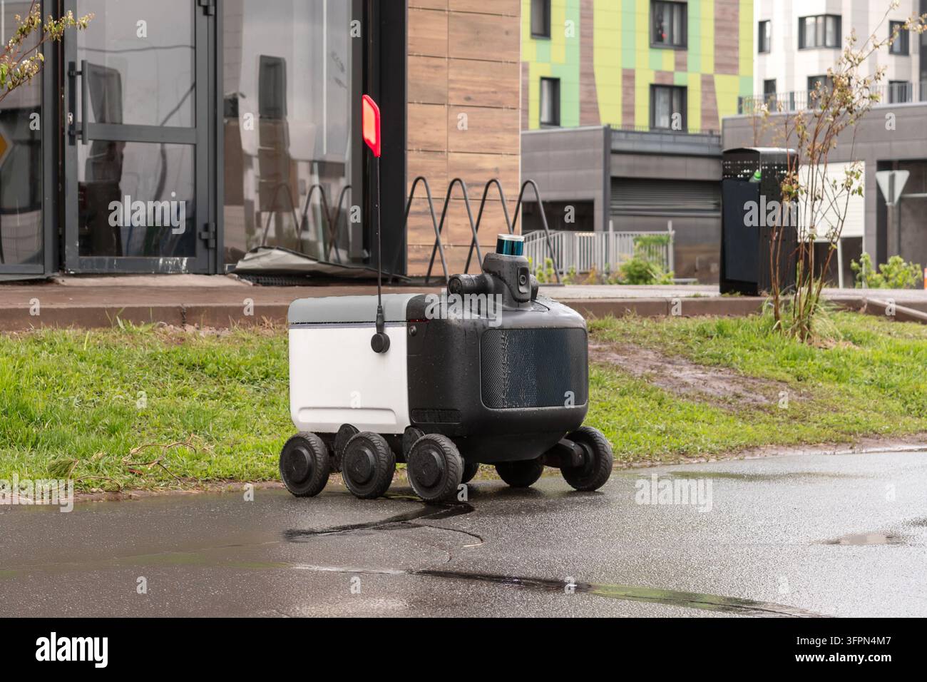 Robot de livraison automatisé moderne debout à l'extérieur attendant une commande par temps pluvieux. Concept moderne de livraison de marchandises au client. Banque D'Images