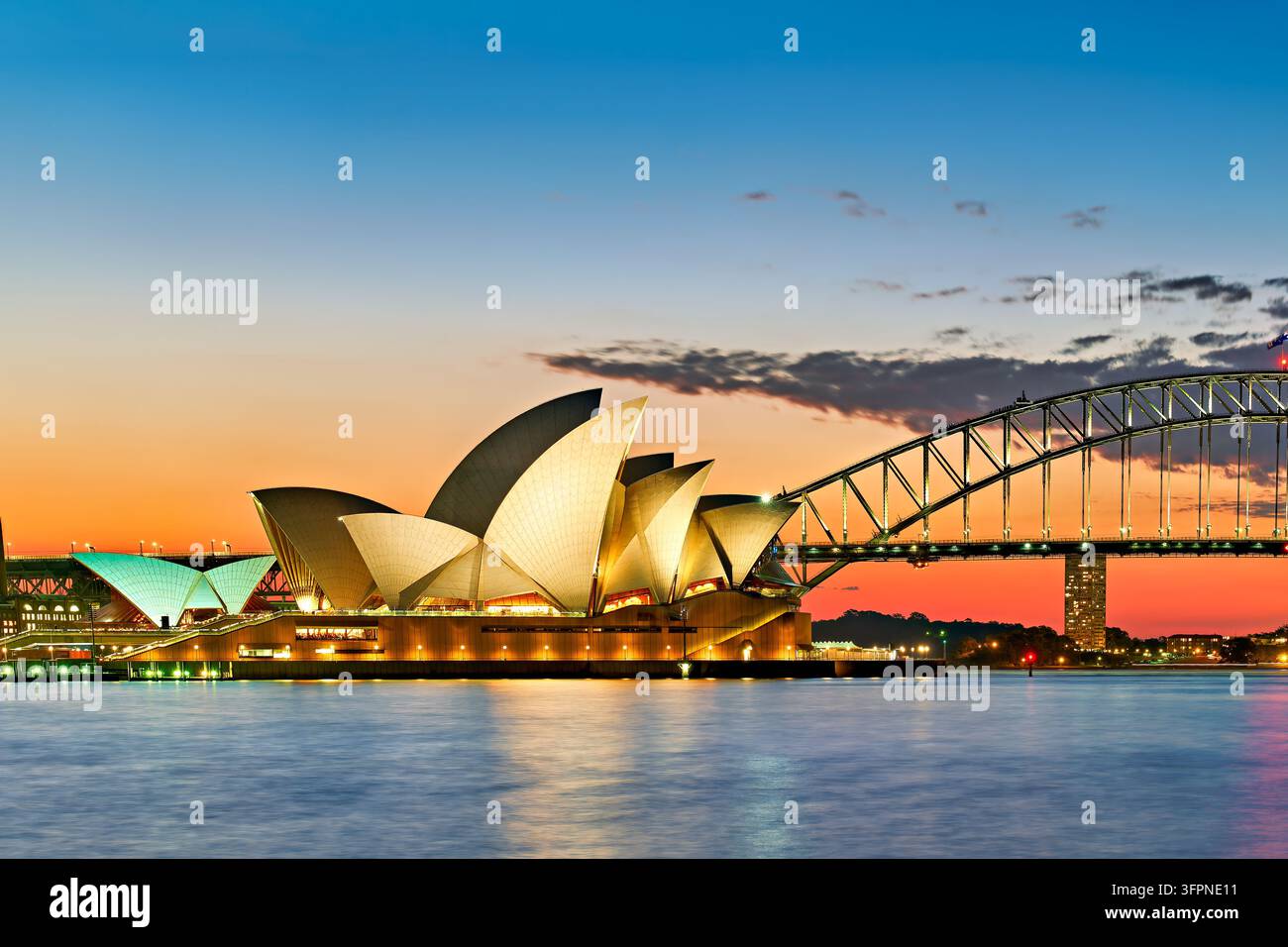 Toits en forme de voile illuminés du centre d'art de Bennelong Point et du pont en arc d'acier traversant le port de Sydney au crépuscule, Nouvelle-Galles du Sud, Australie Banque D'Images