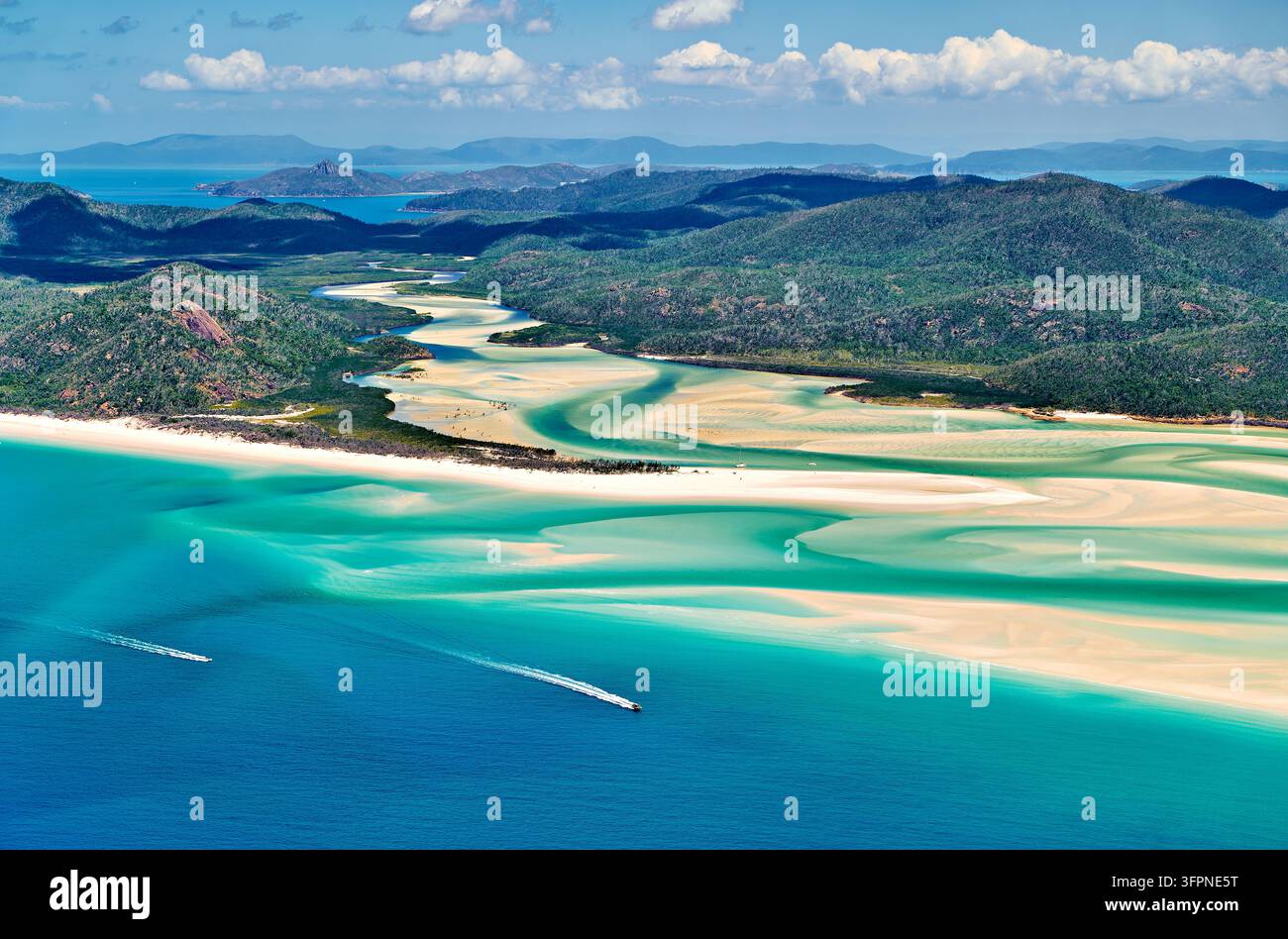 Vue aérienne de canaux de marée turquoise et de tourbillons de sable blanc, avec deux hors-bord au large, dans les Whitsunday Islands, Queensland, Australie Banque D'Images