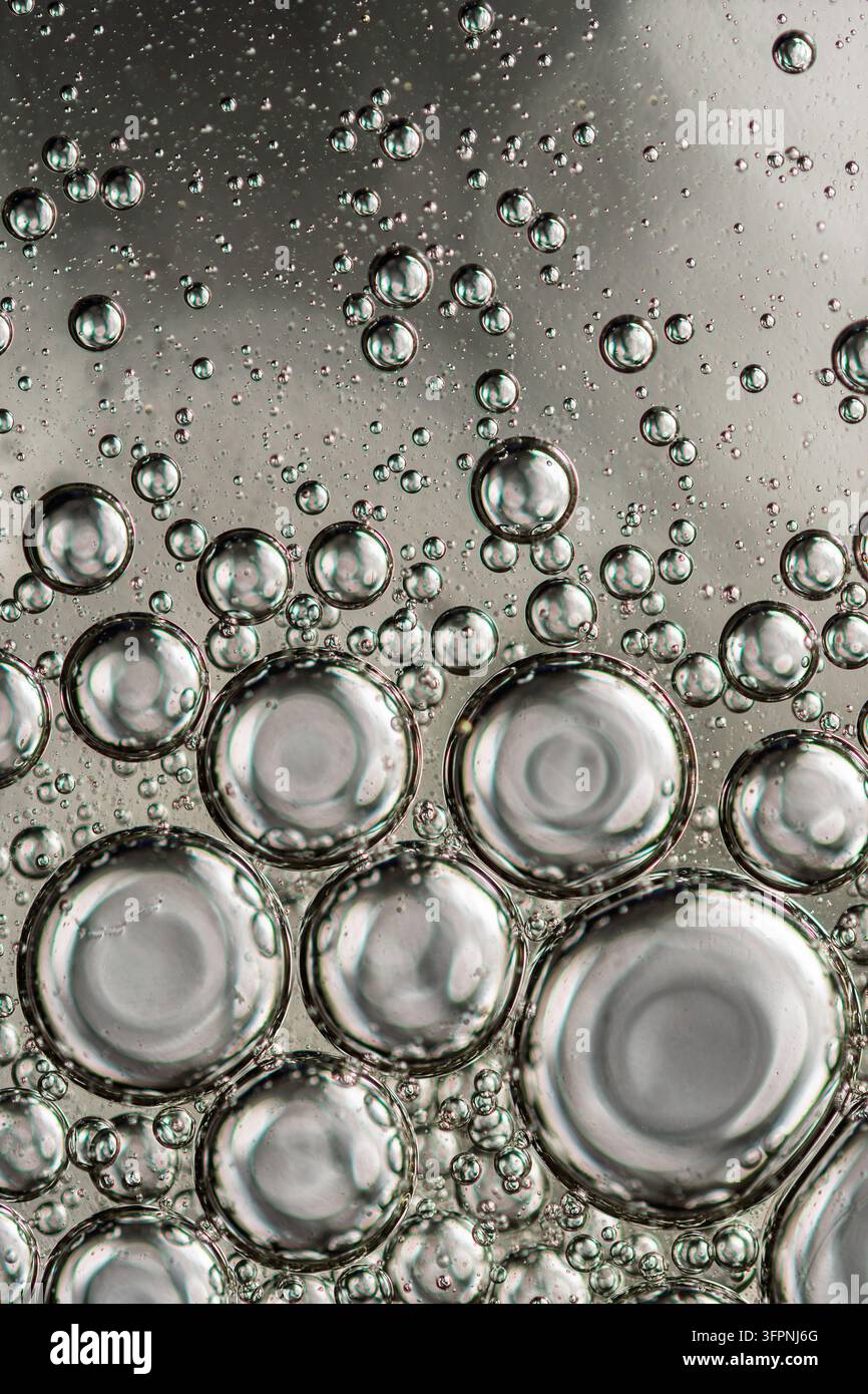 Des bulles de liquide transparent forment des sphères flottantes sur un fond neutre, créant une texture abstraite pour la chimie, la science ou les soins de la peau Banque D'Images