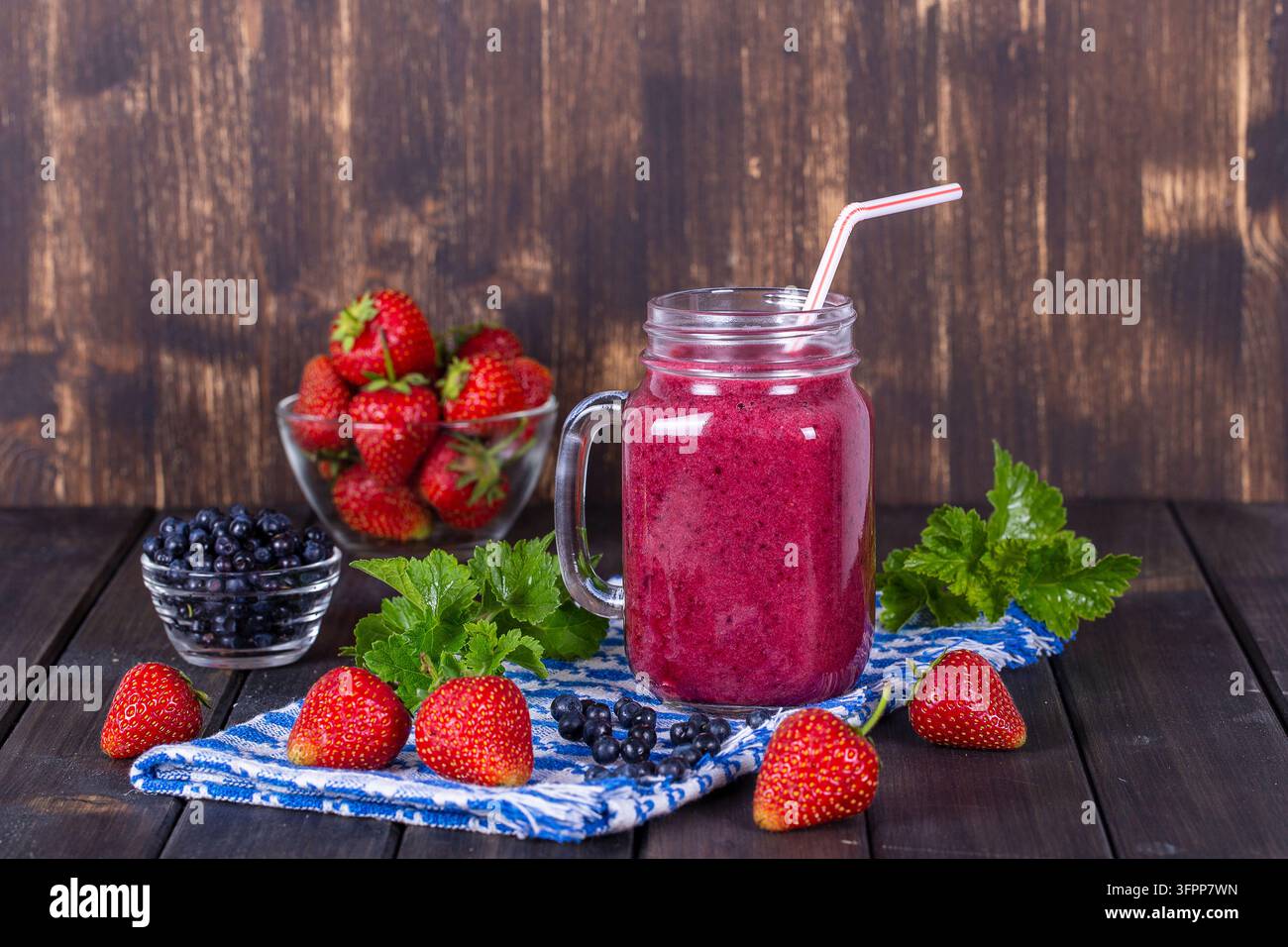 Alimentation saine, nourriture, régime et concept végétarien - smoothie à la fraise, myrtille et banane dans un mug en pot Mason, gros plan Banque D'Images