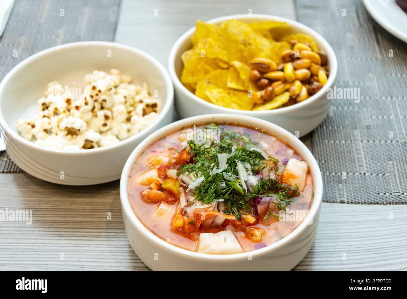 Bol de ceviche aux fruits de mer frais garni d'herbes accompagné de chips de plantain croustillantes et de maïs grillé pour un repas classique sud-américain Banque D'Images
