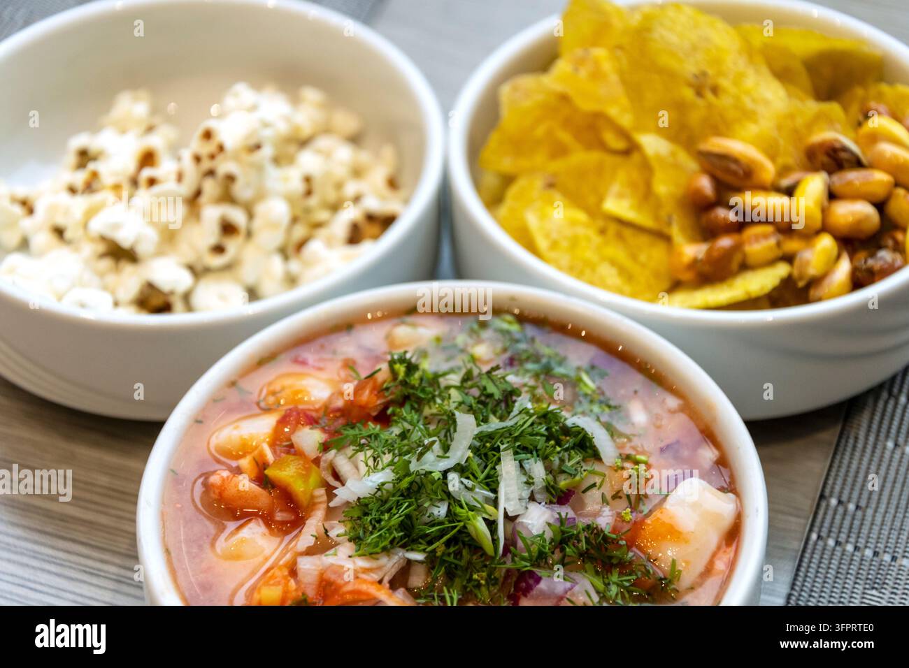 Un bol vibrant de ceviche de fruits de mer frais garni d'herbes accompagné de chips de plantain croustillantes et de maïs grillé pour un repas classique sud-américain Banque D'Images
