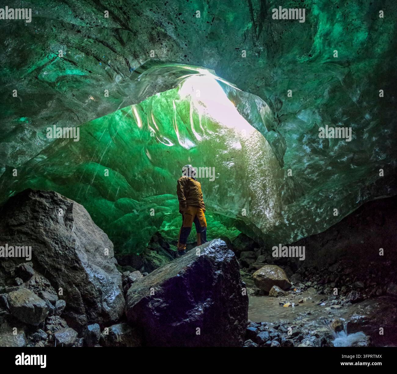 Homme dans une grotte de glace, Kulusuk, Groenland Banque D'Images