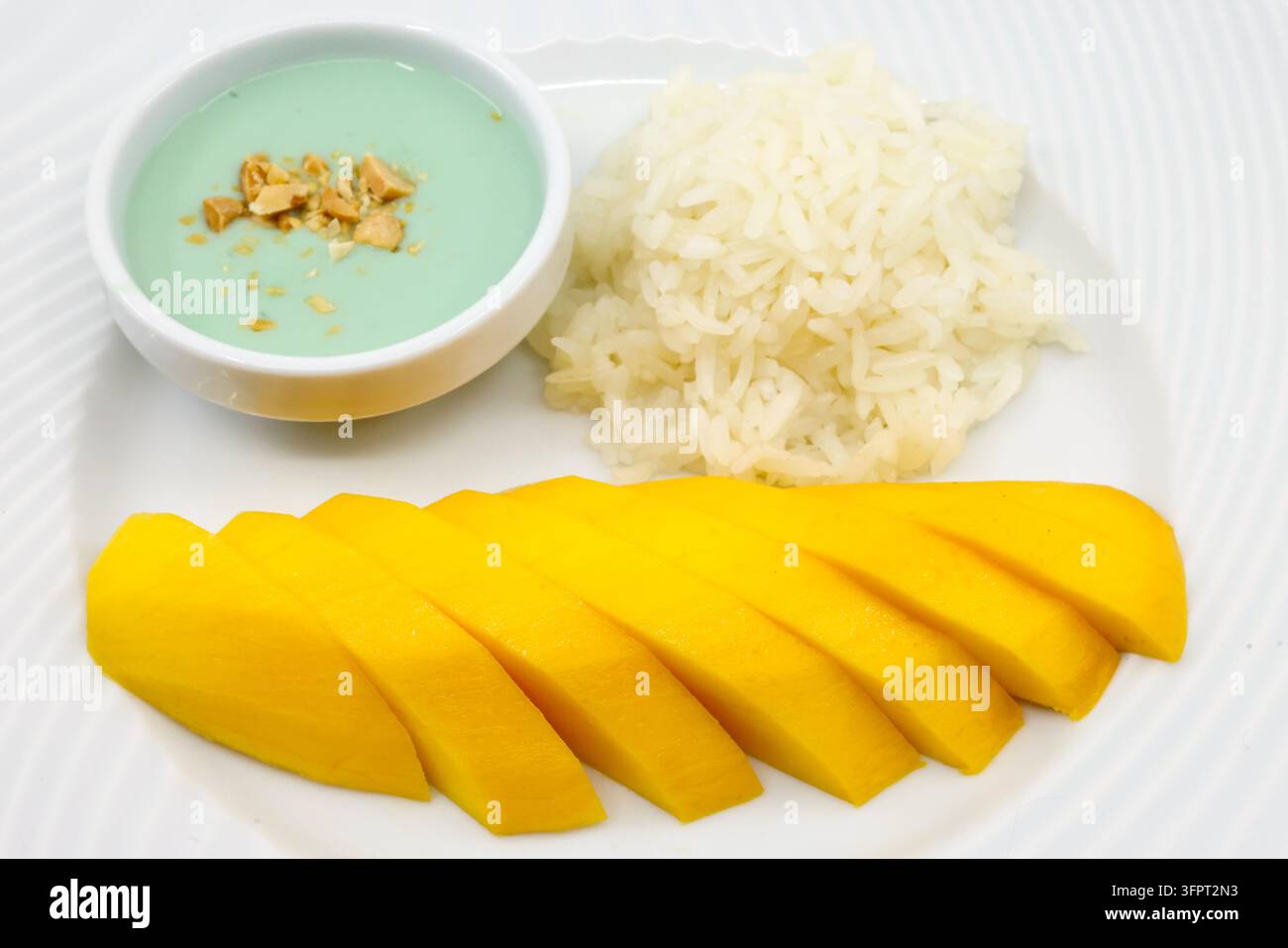 Cuisine asiatique. Dessert classique thaïlandais de riz gluant à la mangue avec sauce à la crème de coco sur une assiette noire. Banque D'Images