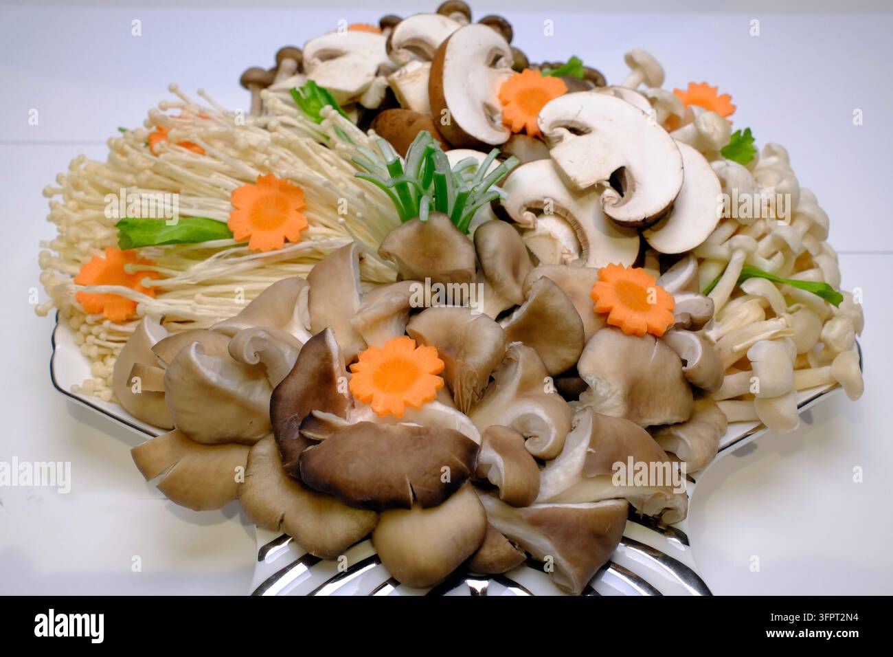 Plat décoratif de champignons en pot chaud magnifiquement arrangé avec des carottes coupées en fleurs et une garniture d'oignon vert. Banque D'Images
