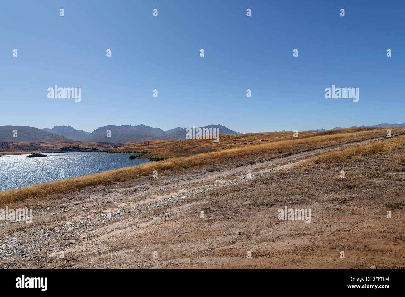 Fond de route, plaque arrière automobile, environnement lacustre offrant une vue élevée sur une piste non goudronnée en milieu montagneux Banque D'Images