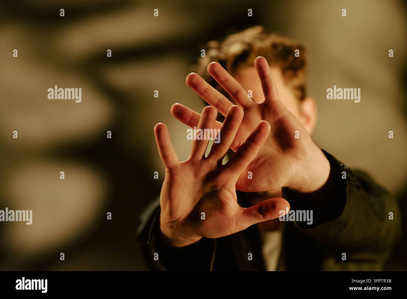 Homme cachant son visage avec les mains ouvertes exprimant la peur et le rejet Banque D'Images