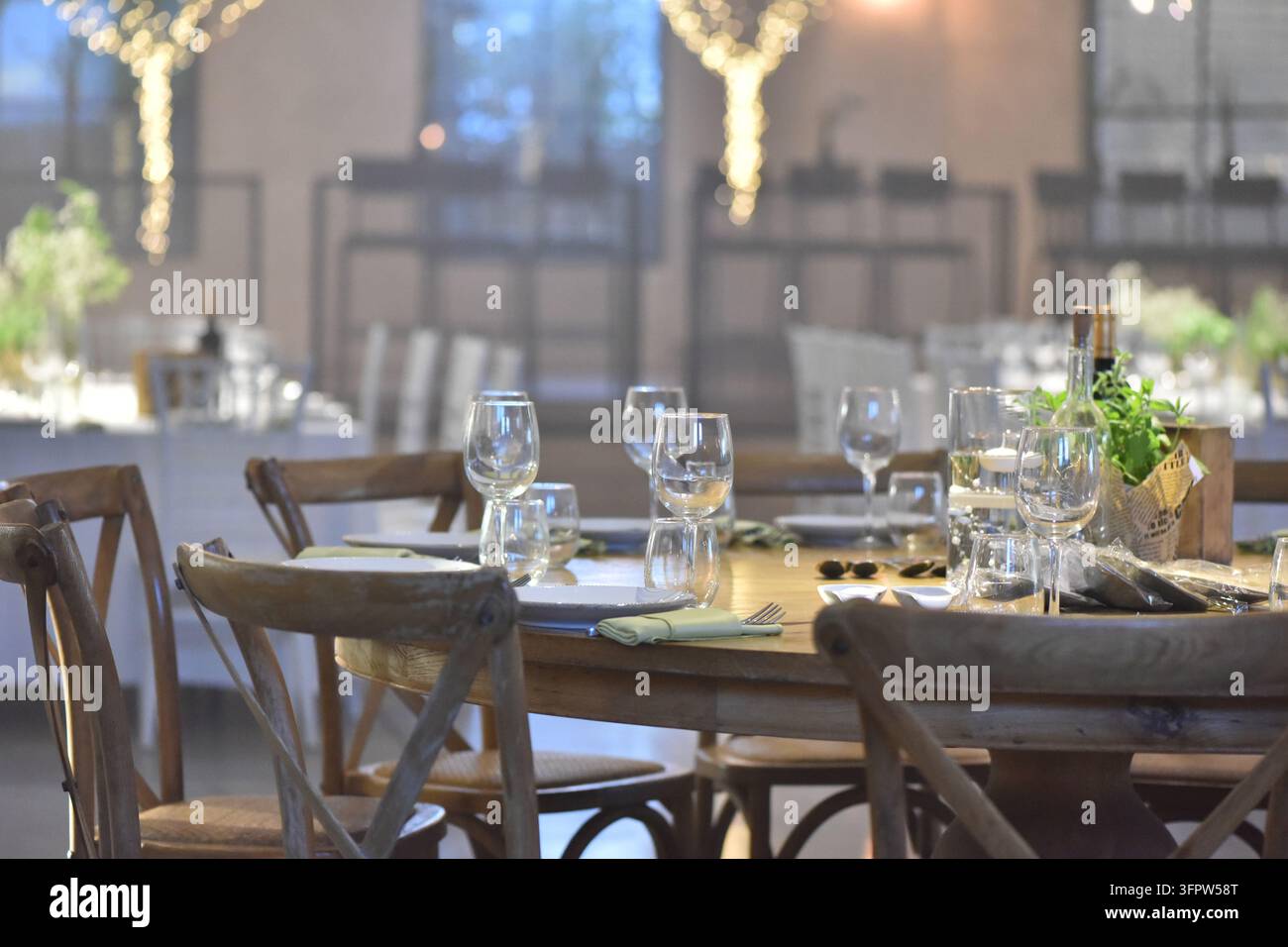 Configuration élégante de table à manger avec des chaises en bois et des verres à vin dans un lieu de mariage Banque D'Images