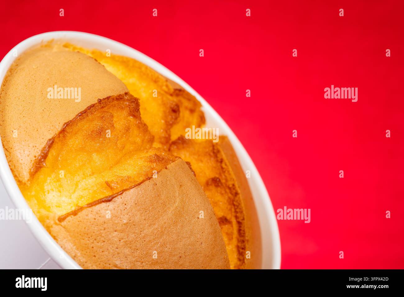 Gâteau souflé moelleux placé dans une tasse blanche sur un fond rouge vif Banque D'Images
