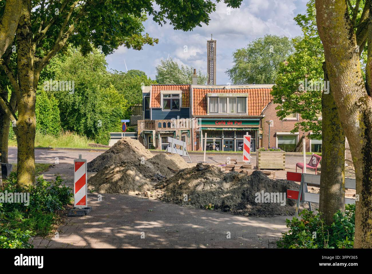 Moerdijk, Pays-Bas – 4 juin 2026 : Travaux routiers avec un vieux café sur la digue, tas de sable et barrières de chantier par une journée ensoleillée, entretien des infrastructures et développement urbain dans un site historique Banque D'Images