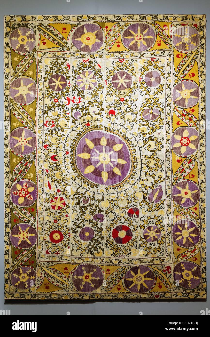 Grand tapis textile brodé suzani présentant des médaillons floraux complexes, des bordures ornementales et des tons riches en violet, or et rouge. Centra traditionnel Banque D'Images
