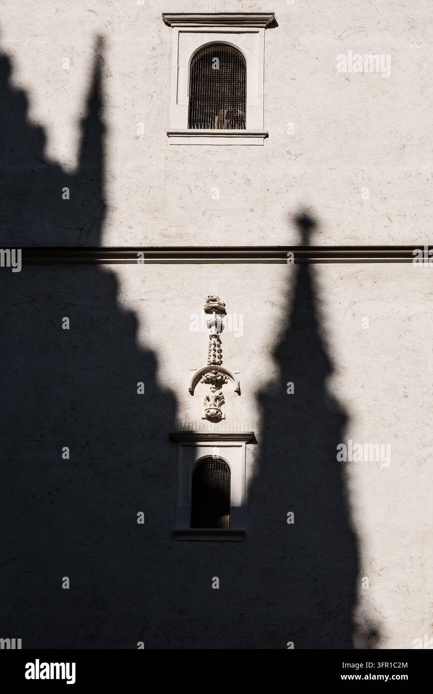L'ombre d'une église à flèche gothique projetée sur un mur de pierre historique avec une petite fenêtre en arc dans la vieille ville de Košice en Slovaquie lors d'une journée ensoleillée et lumineuse créant un effet dramatique Banque D'Images