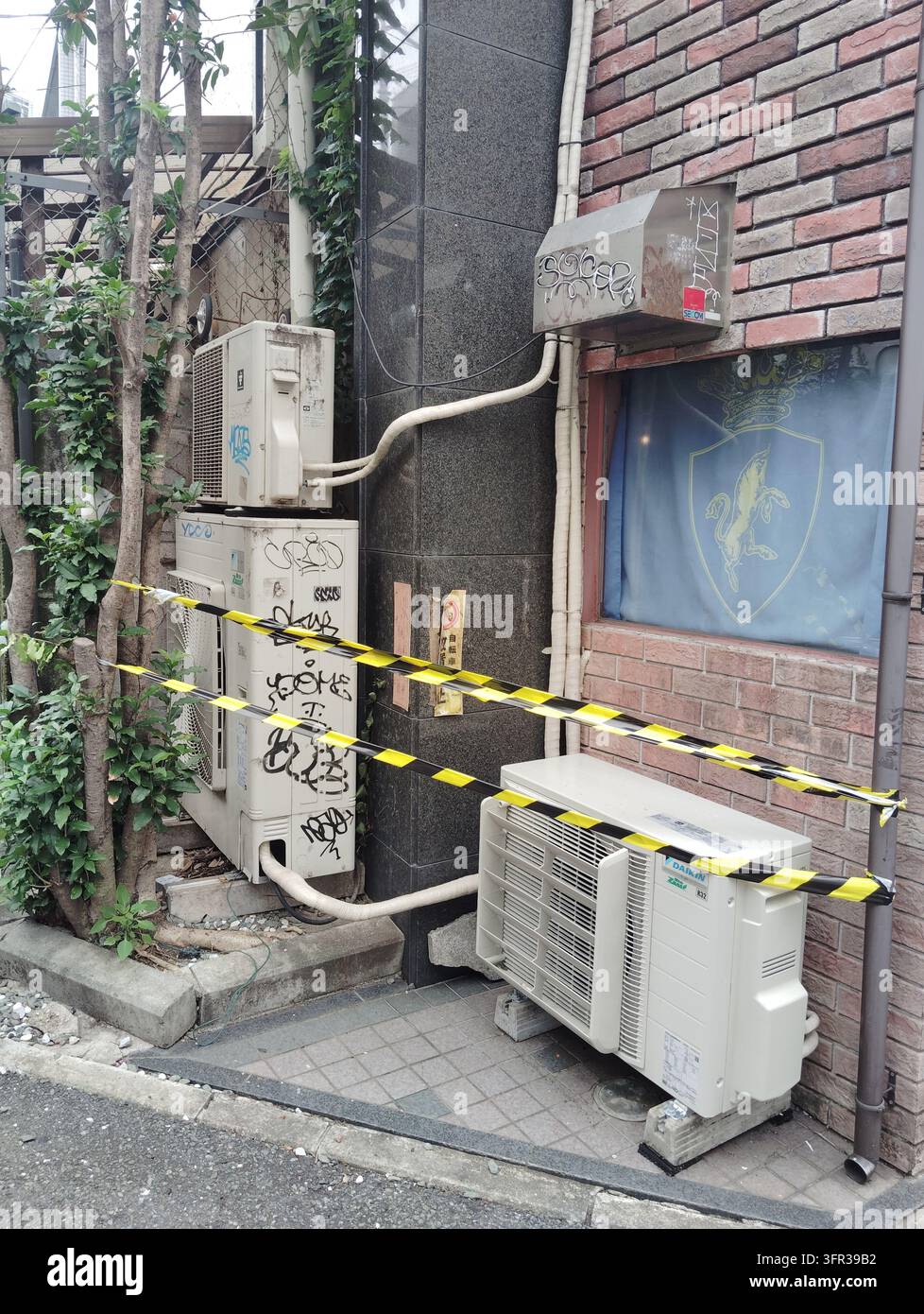 Unités de climatisation et équipements utilitaires couverts de graffitis à l'extérieur d'un bâtiment à Tokyo, Japon. - Image de stock capturée avec un smartphone