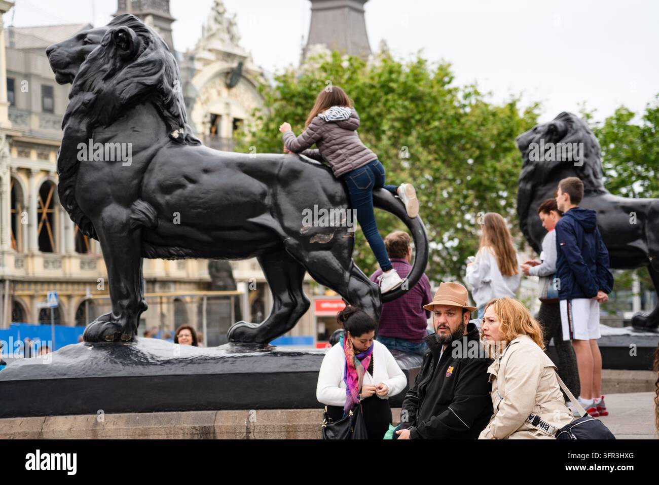 TOURISTES SE RÉUNISSENT AUTOUR D'UNE STATUE DE LION, REPORTAGE PHOTOGRAPHIQUE DE RUE À BARCELONE, BARCELONE, ESPAGNE, 2019 : Une foule de touristes se rassemble autour d'une grande statue de lion noir sur une place de la ville, plusieurs personnes, dont une jeune femme en jean, grimpant sur son dos. INFO : Barcelone est une ville côtière espagnole vibrante, réputée pour son architecture emblématique, ses plages méditerranéennes, le quartier gothique historique, sa riche culture catalane, le football de classe mondiale et une atmosphère métropolitaine animée remplie d'art, de nourriture et de musique. Banque D'Images
