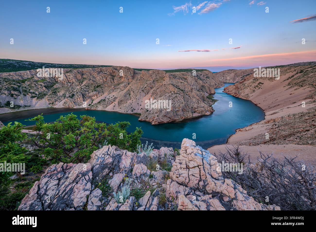 Vue élevée depuis Winnetou Point sur le canyon de la rivière Zrmanja près de Jasenice, montrant des falaises rocheuses et une rivière sinueuse au lever du soleil. Banque D'Images