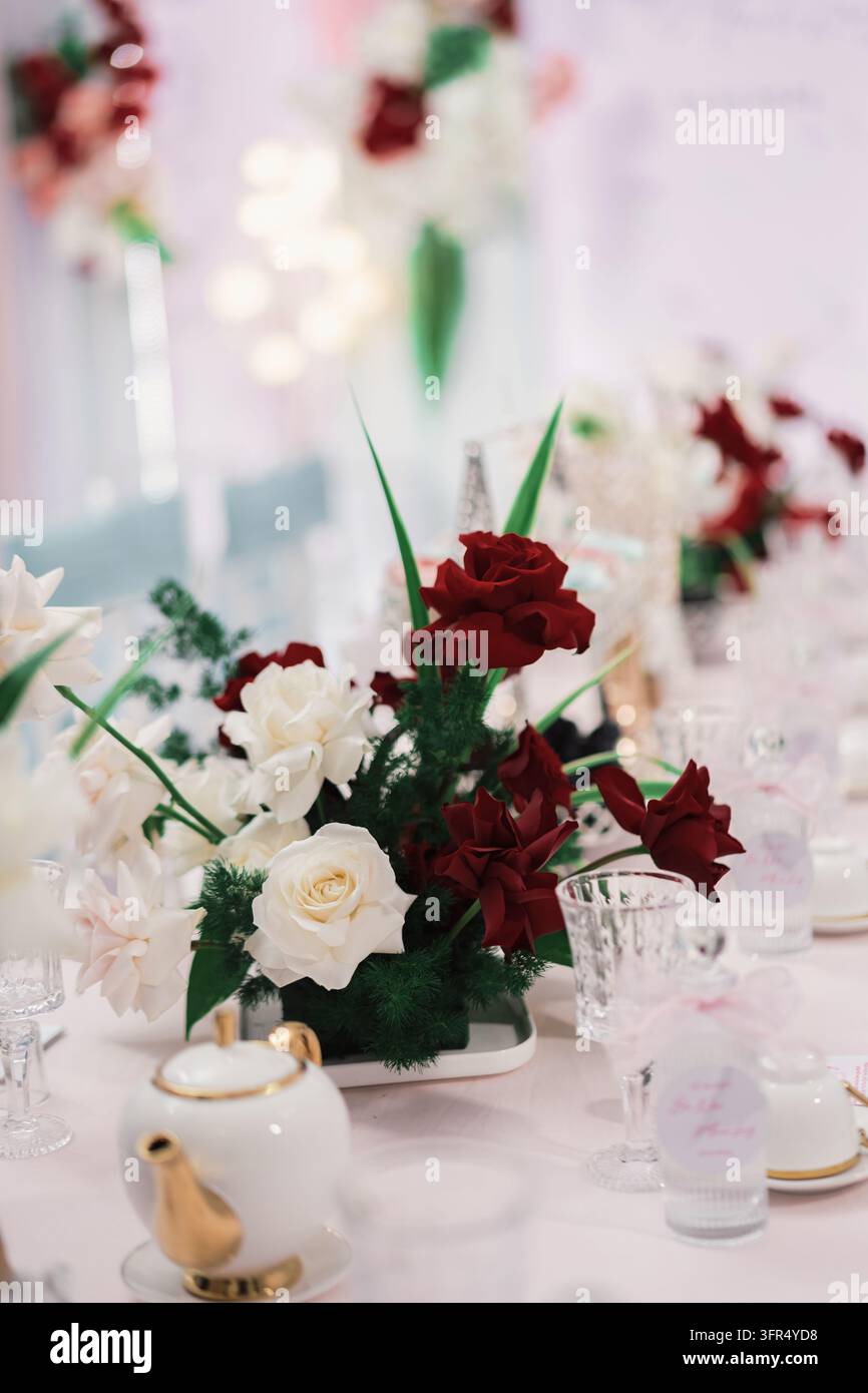 Centre de table floral élégant avec des roses rouges et blanches sur une table de réception de mariage festive Banque D'Images