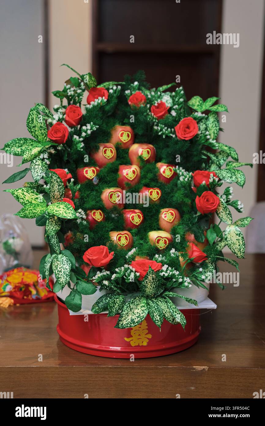 Panier cadeau de fruits traditionnel pour un mariage chinois avec des pommes et des roses rouges Banque D'Images