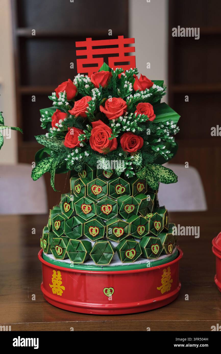 Panier cadeau de mariage chinois traditionnel décoré de feuilles vertes pliées et de roses rouges avec un signe de double bonheur Banque D'Images