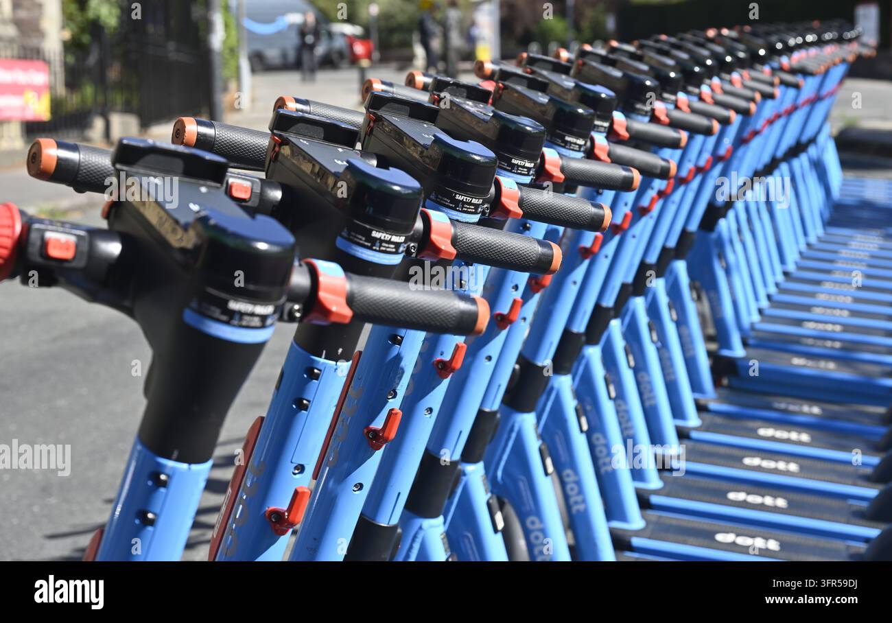 Rangée soignée de scooters électriques à la location attendant des clients à l'extérieur dans la rue Banque D'Images