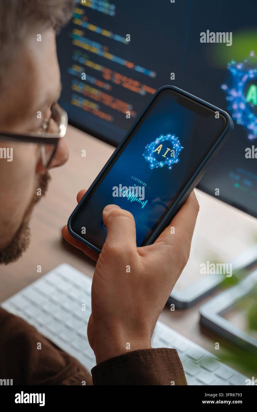 Gros plan d'un homme tenant un smartphone parlant à un assistant vocal personnel alimenté par l'IA utilisant l'intelligence artificielle sur le téléphone et l'ordinateur, interagissant avec une application de chatbot IA ou donnant des tâches à un agent IA.  Banque D'Images