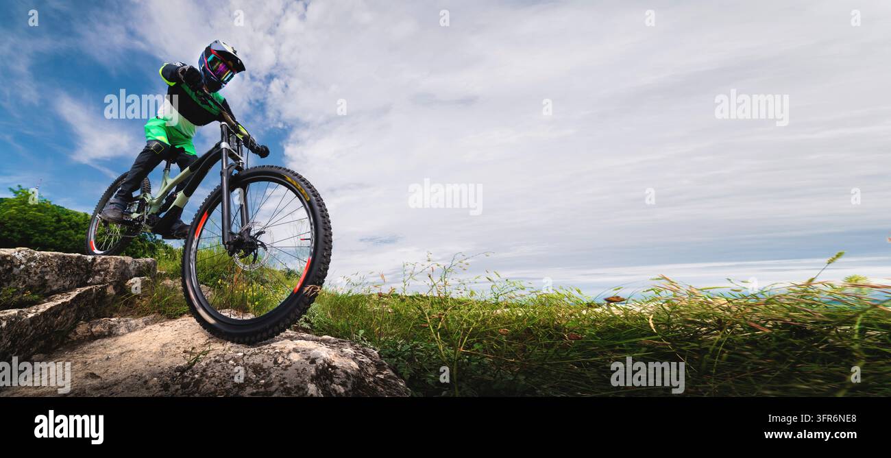 Sport. Un homme en vêtements de protection sur un VTT sur un rocher. Un homme en T-shirt vert vif descend rapidement la montagne. Sport extrême Banque D'Images