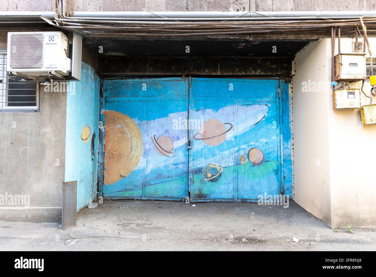Porte de garage peinte d'une fresque colorée de planètes et d'un système solaire à côté d'une unité de climatisation, Erevan, Erevan, Arménie Banque D'Images
