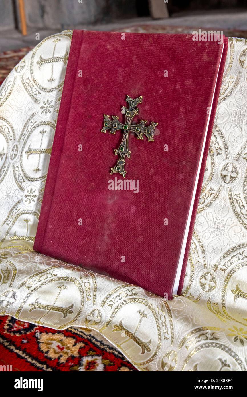 Un livre de prières en velours rouge décoré d'une croix en métal repose sur un tissu brodé à l'intérieur de l'église de Vahramashen, province d'Aragatsotn, Amberd, Arménie Banque D'Images