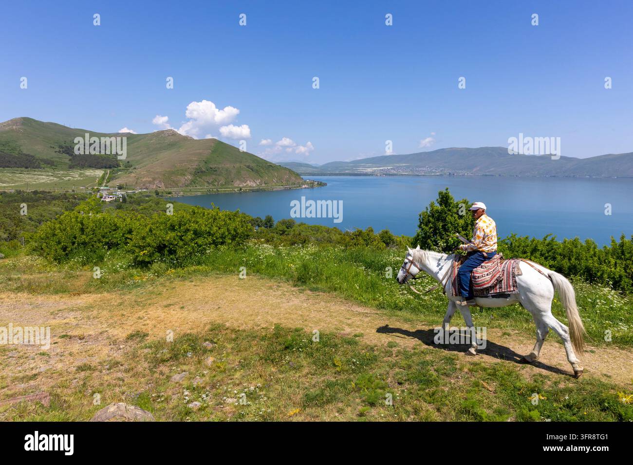 Homme montant un cheval blanc le long de la rive du lac Sevan, province de Gegharkunik, Sevanavank, Arménie Banque D'Images