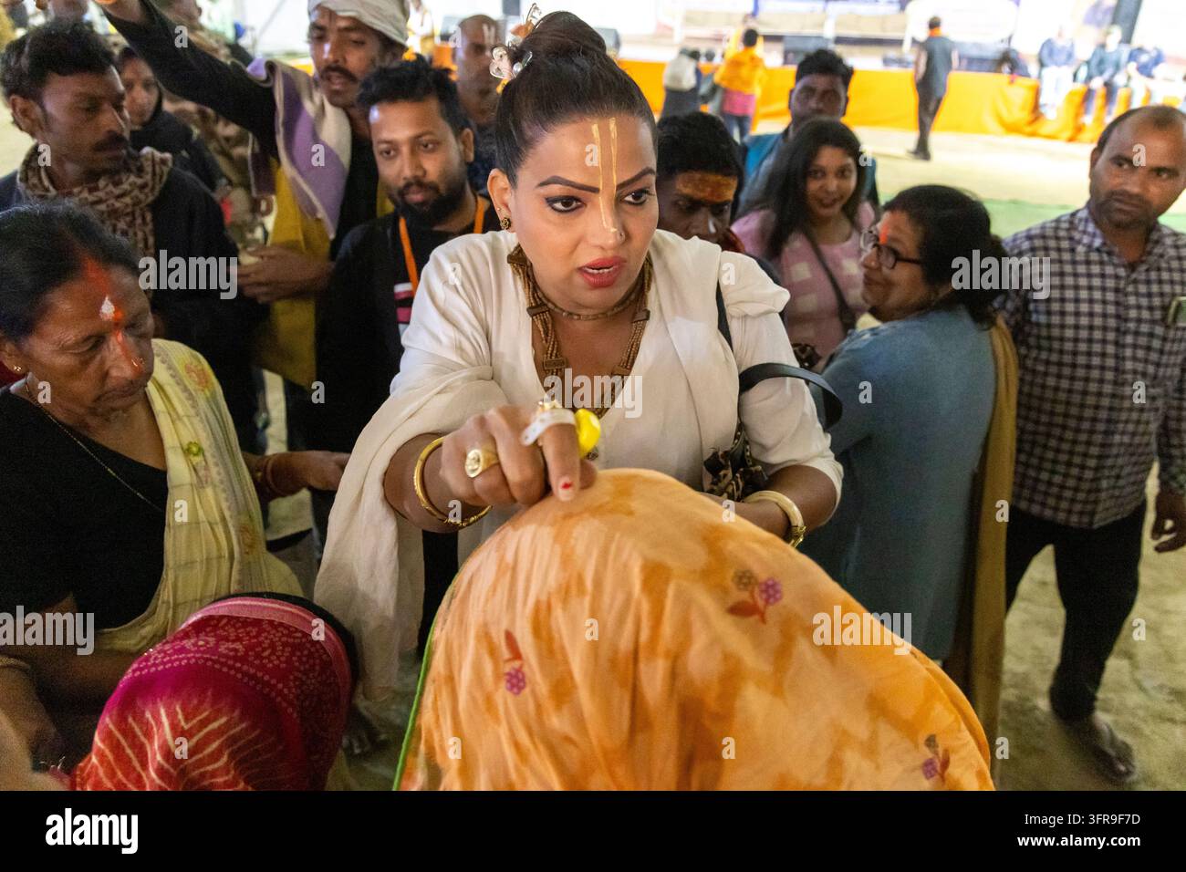 Hijra portant des marques tilak dans un châle blanc donne une bénédiction à une foule de dévots lors du Maha Kumbh Mela, Uttar Pradesh, Prayagraj, Inde Banque D'Images