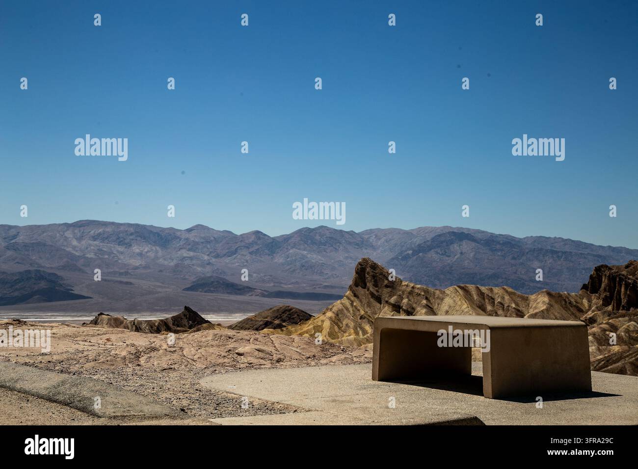 Un banc de vue en béton surplombant les badlands érodées et colorées de Zabriskie Point dans le parc national de Death Valley, Californie, États-Unis Banque D'Images