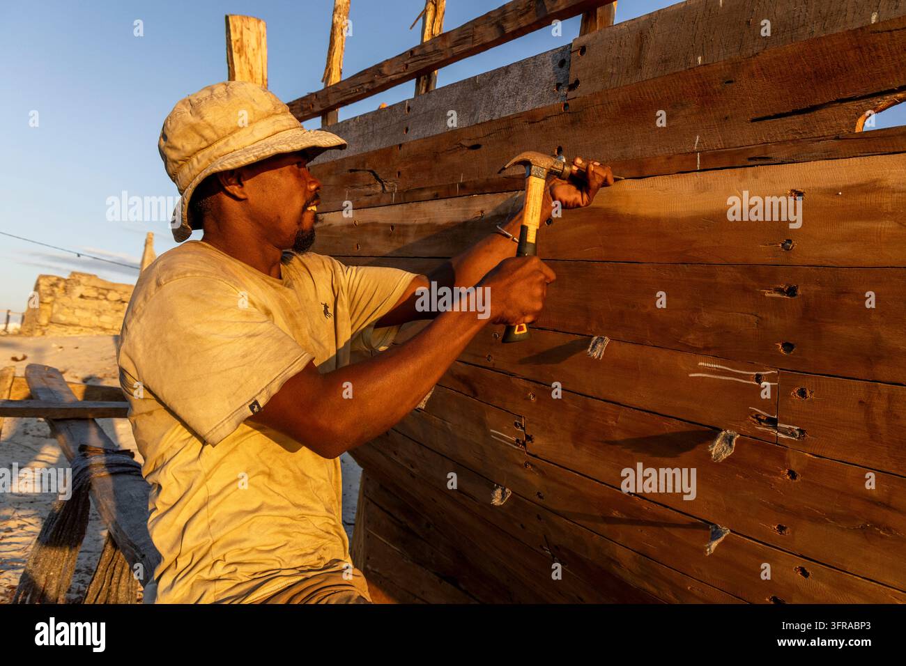 Homme Vezo enfonçant un clou dans la coque en bois d'un bateau lors de la construction d'un navire traditionnel, Menabe, Belo sur Mer, Madagascar Banque D'Images