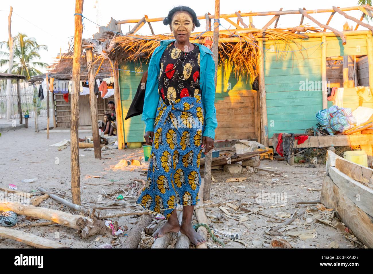 Femme Vezo portant une pâte de masque traditionnel debout parmi des châssis de bateaux en bois dans le village, Menabe, Belo sur Mer, Madagascar Banque D'Images