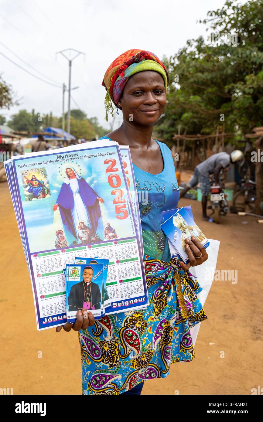 Femme vendant des calendriers religieux et des portraits sur un marché de rue, Région Maritime, Togoville, Togo Banque D'Images