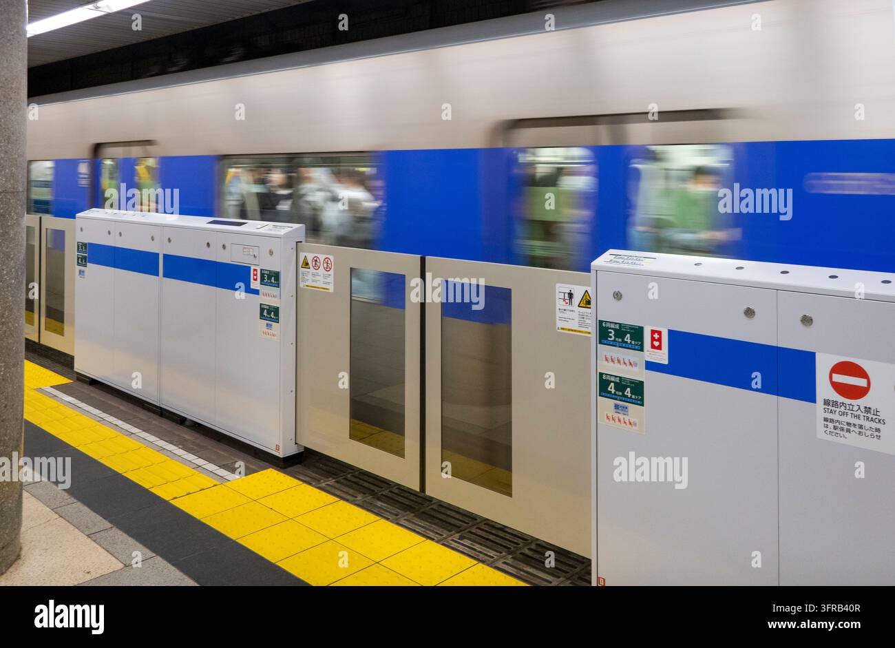 Japon, Tokyo, train de métro de la ligne Mita quittant la station, avec les barrières de sécurité fermées Banque D'Images