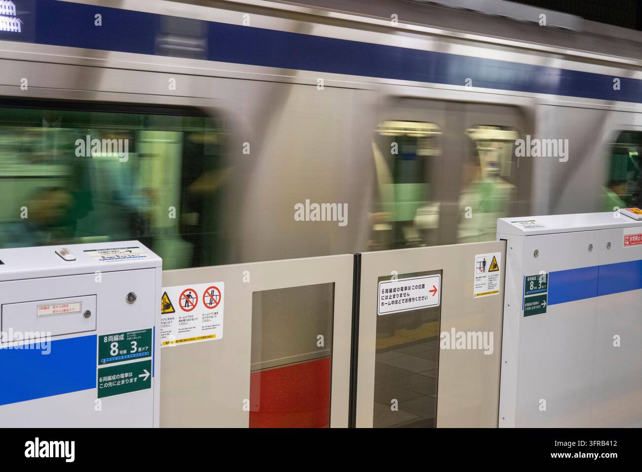 Japon, Tokyo, train de métro de la ligne Mita quittant la station, avec les barrières de sécurité fermées Banque D'Images