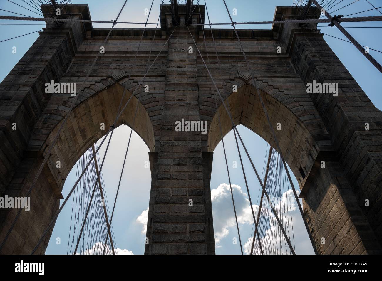 2019 New York City, États-Unis ; Vue en contre-plongée des arches gothiques et de la tour en pierre du pont de Brooklyn avec les câbles de suspension contre un ciel bleu Banque D'Images