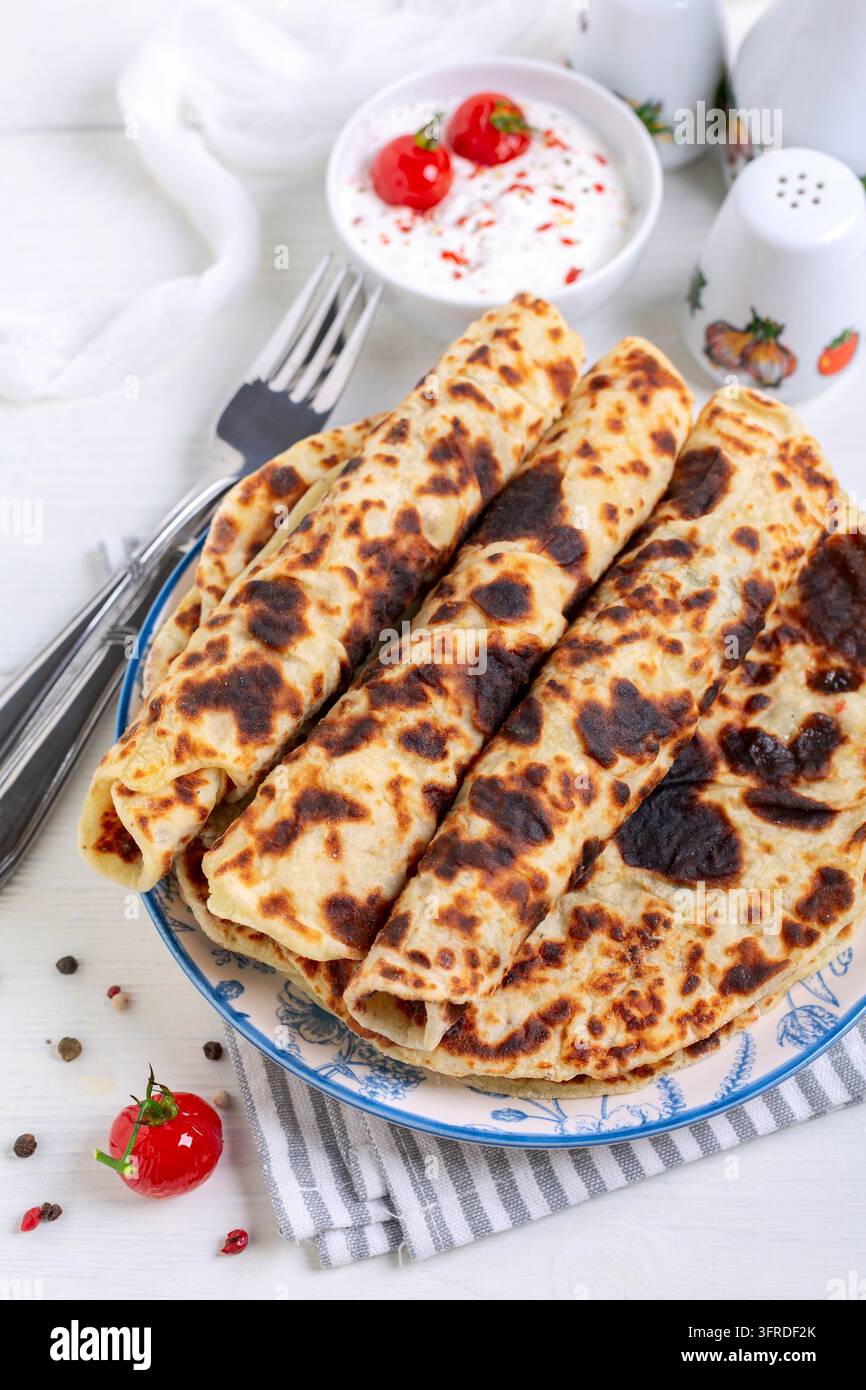 Lefse norvégien traditionnel – crêpes fines de pommes de terre avec sauce à la crème fraîche et tomates cerises caramélisées, mise au point sélective Banque D'Images